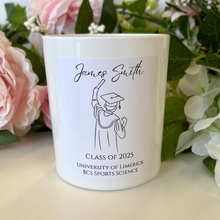 Load image into Gallery viewer, A personalised graduation candle in a clear glass jar with a custom label displaying the graduate’s name, degree, and graduation year.