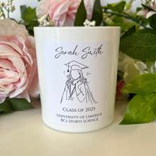 Load image into Gallery viewer, A personalised graduation candle in a clear glass jar with a custom label displaying the graduate’s name, degree, and graduation year.